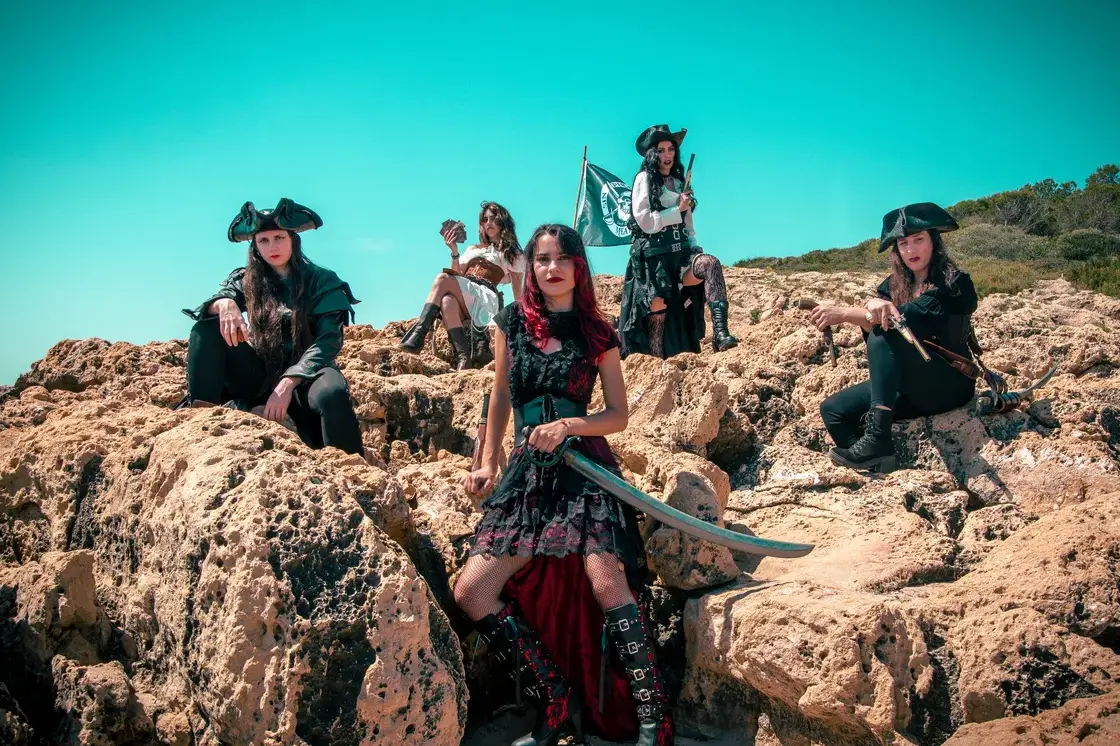 La banda Pirate Queen posando entre rocas con vestuario pirata