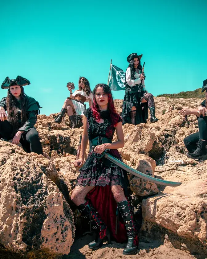 La banda Pirate Queen posando entre rocas con vestuario pirata