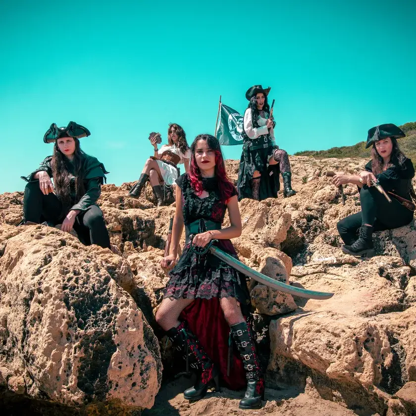 La banda Pirate Queen posando entre rocas con vestuario pirata