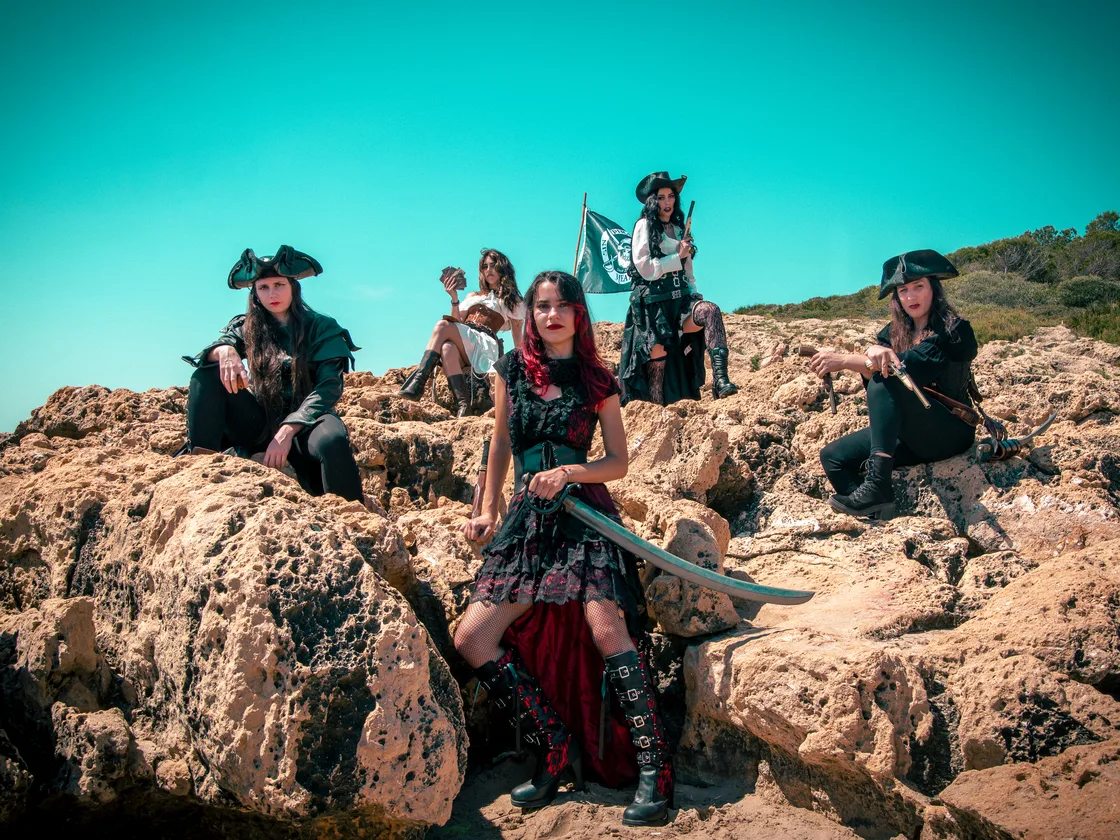 La banda Pirate Queen posando entre rocas con vestuario pirata